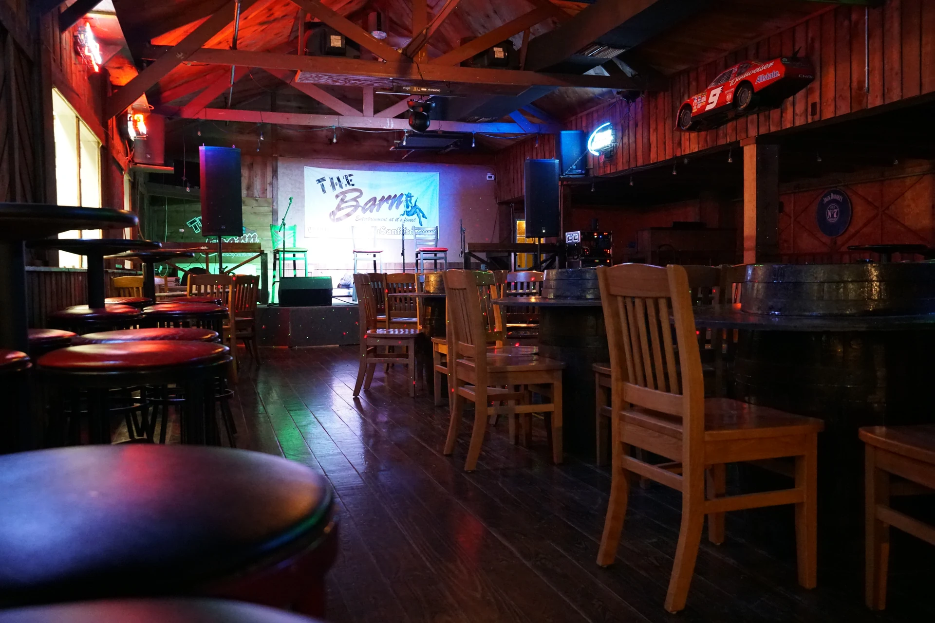 Wooden tables and seating facing The Barn’s illuminated stage